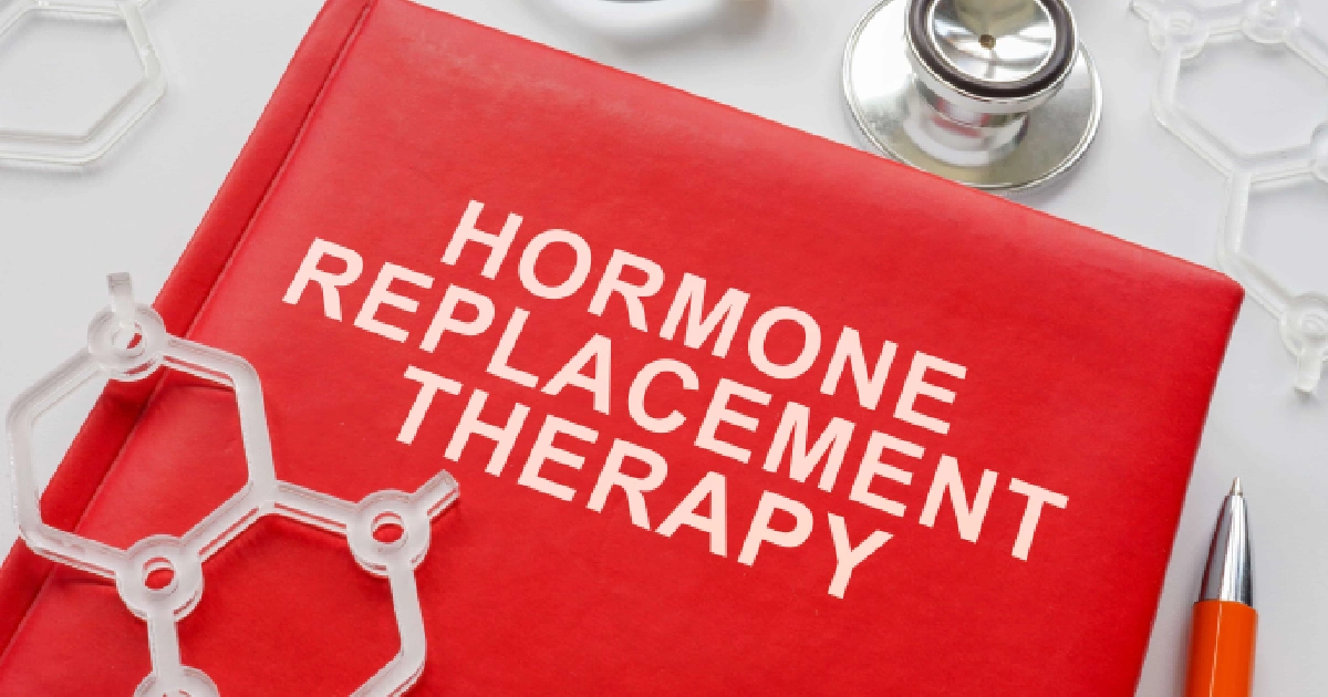Red HRT book with stethoscope, pen, and hormone models on white, representing Hormone Rejuvenation Therapy in Goldsboro, NC.